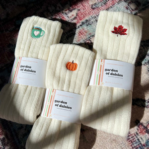 Three pairs of socks with embroidered designs on a textured surface