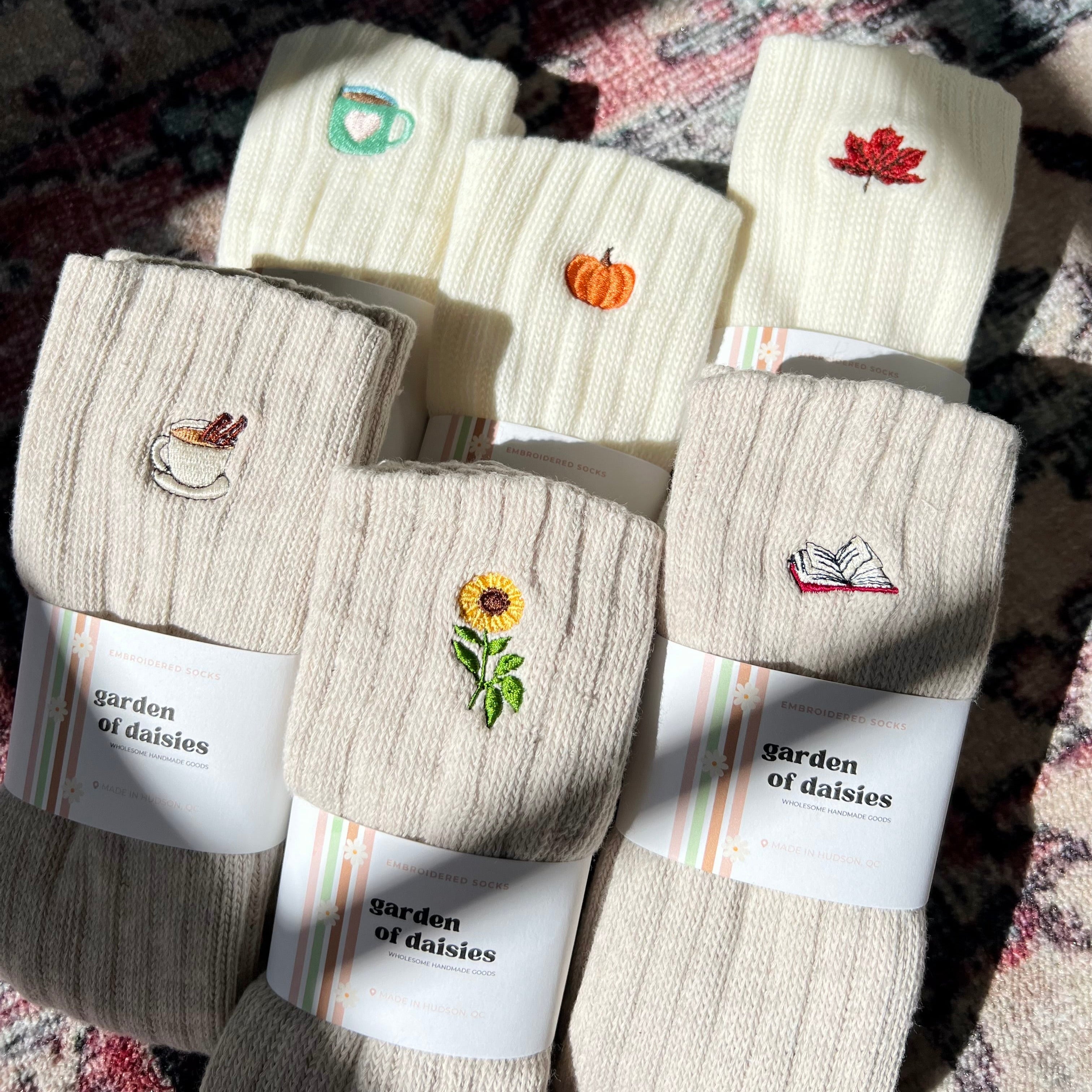Set of beige socks with embroidered designs on a patterned surface
