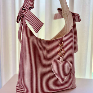 Red and white striped tote bag with a keychain on a light background