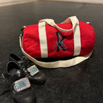 Load image into Gallery viewer, Red duffel bag with white strap and black shoes on a dark surface
