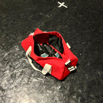Load image into Gallery viewer, Red bag with contents on a black textured surface
