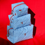 Load image into Gallery viewer, Set of blue checkered bags with red zippers on a red background

