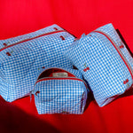 Load image into Gallery viewer, Set of blue checkered bags with red zippers on a red background
