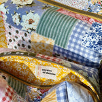 Load image into Gallery viewer, Patchwork-style fabric bags with floral, checkered, and striped patterns on a yellow floral background.
