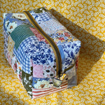 Load image into Gallery viewer, Patchwork-style makeup bag with floral and gingham patterns on a yellow floral background
