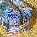 Load image into Gallery viewer, Patchwork-style pouch with floral and plaid patterns on a yellow floral background
