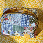 Load image into Gallery viewer, Patchwork-style fabric bag on a yellow floral background
