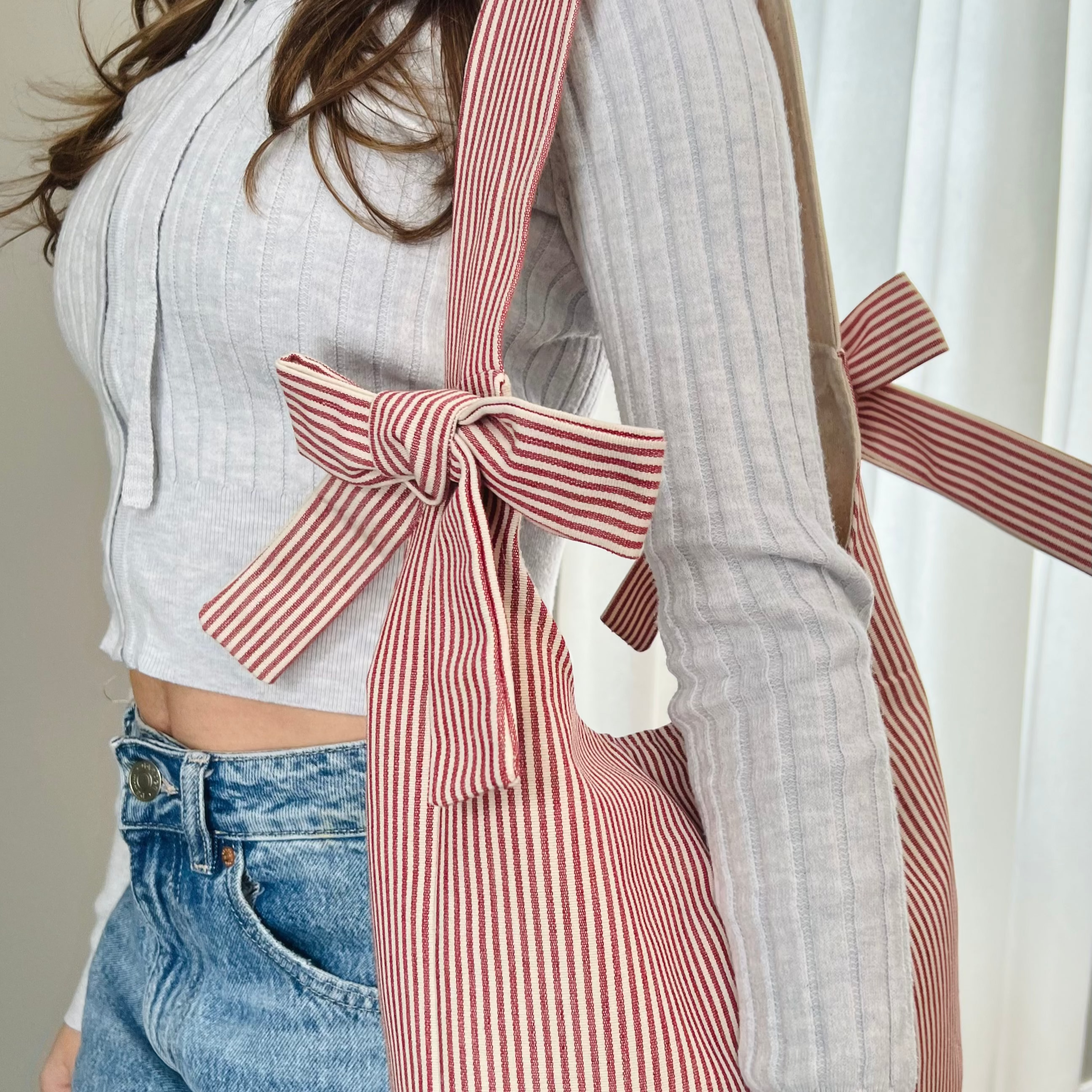 Person wearing a striped apron with a bow, standing indoors.