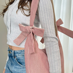 Load image into Gallery viewer, Person wearing a striped apron with a bow, standing indoors.
