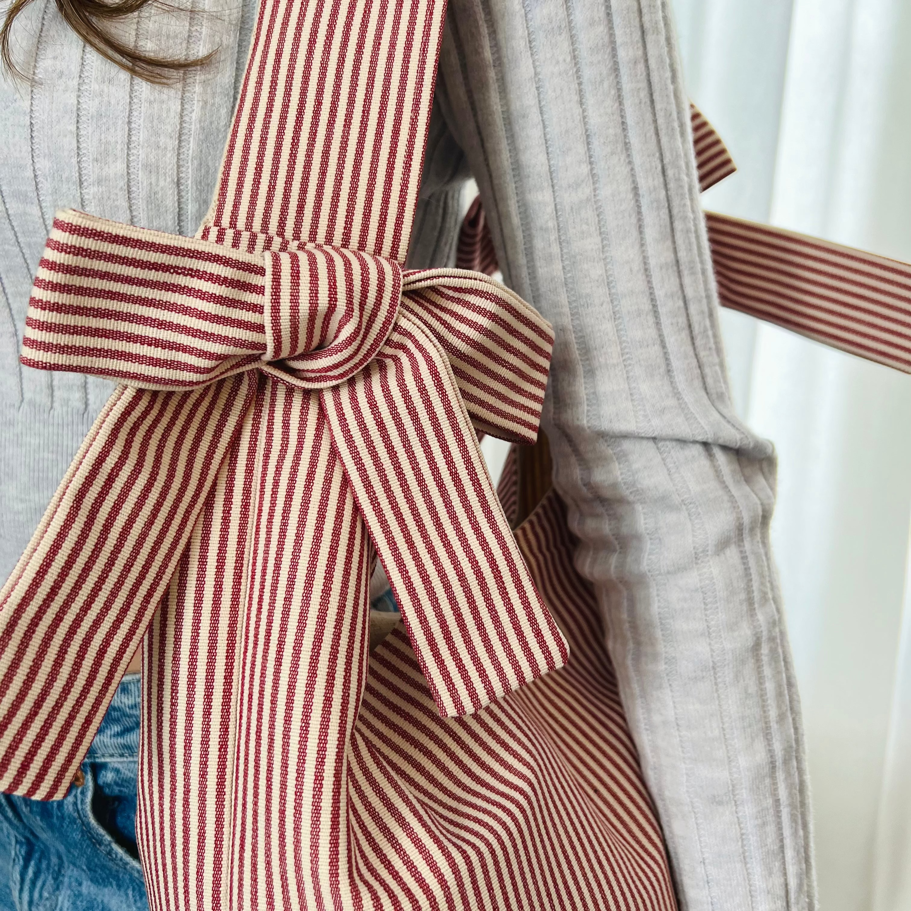 Person wearing a coat with a red and white striped bow detail