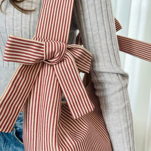 Person wearing a coat with a red and white striped bow detail