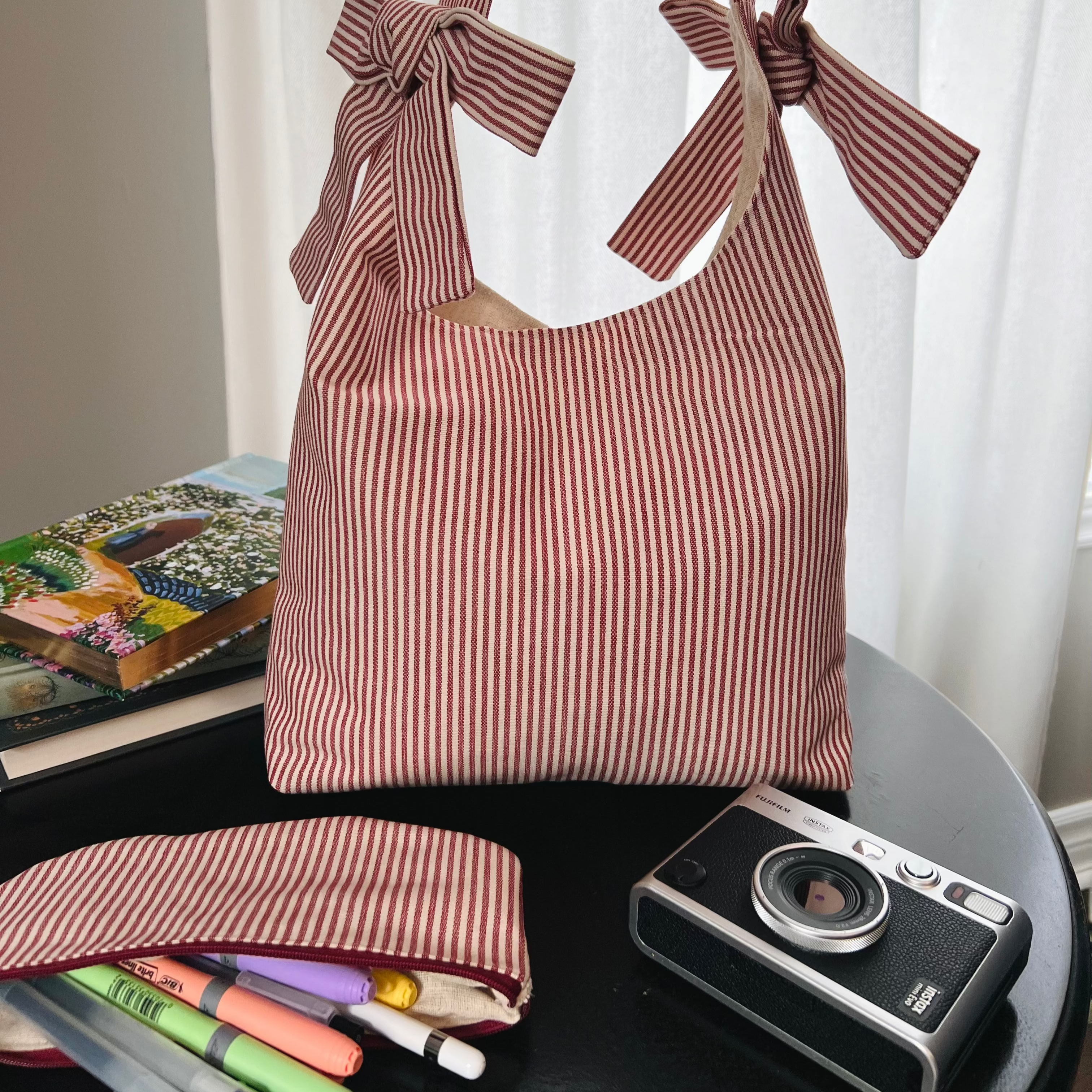 Striped handbag with bow details on a table with stationery items