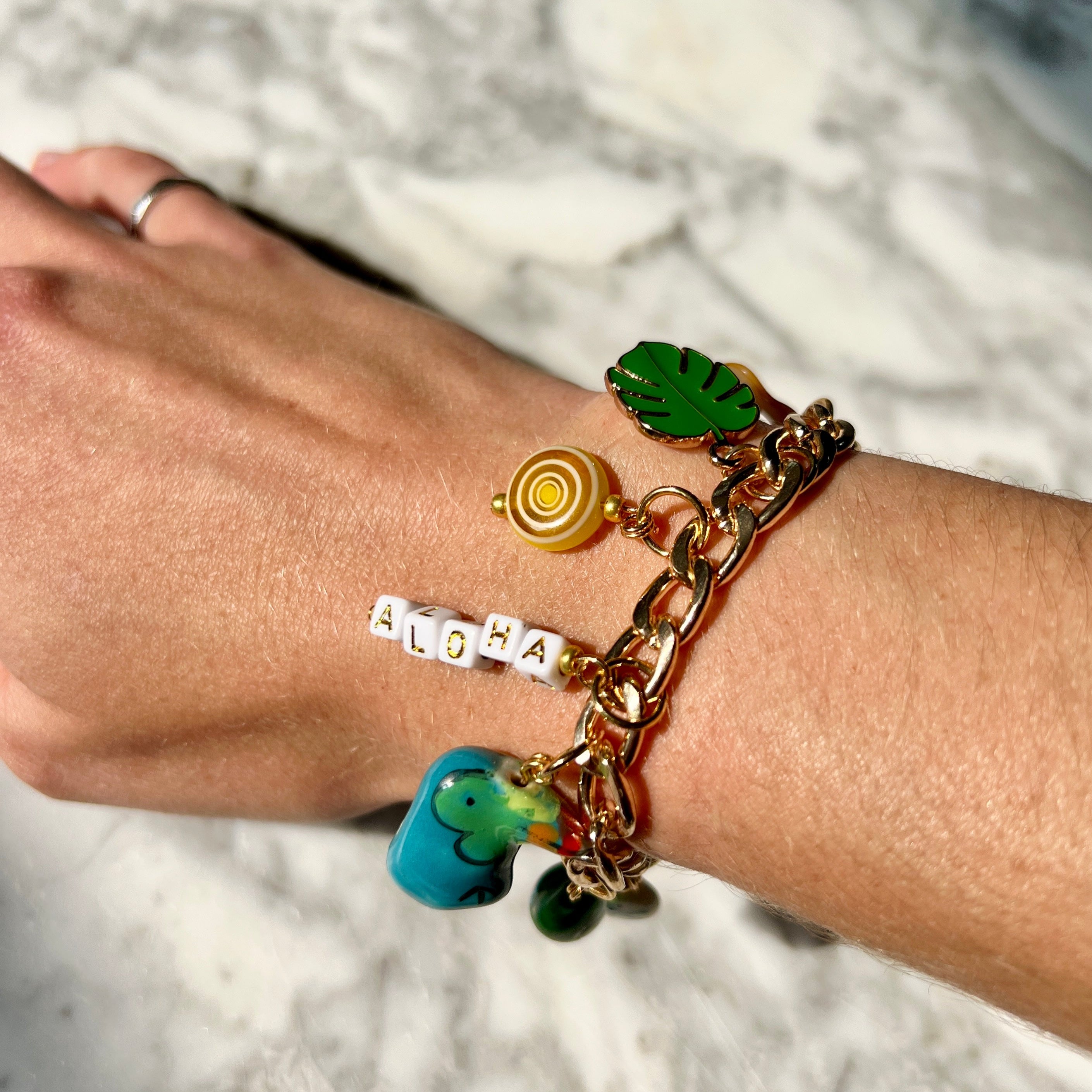 Bracelet with various charms on a wrist against a marble background