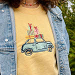 Load image into Gallery viewer, Person wearing a yellow shirt with a car and gift box design, outdoors.
