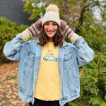 Load image into Gallery viewer, Woman wearing a denim jacket, yellow shirt, and knit hat outdoors with trees in the background
