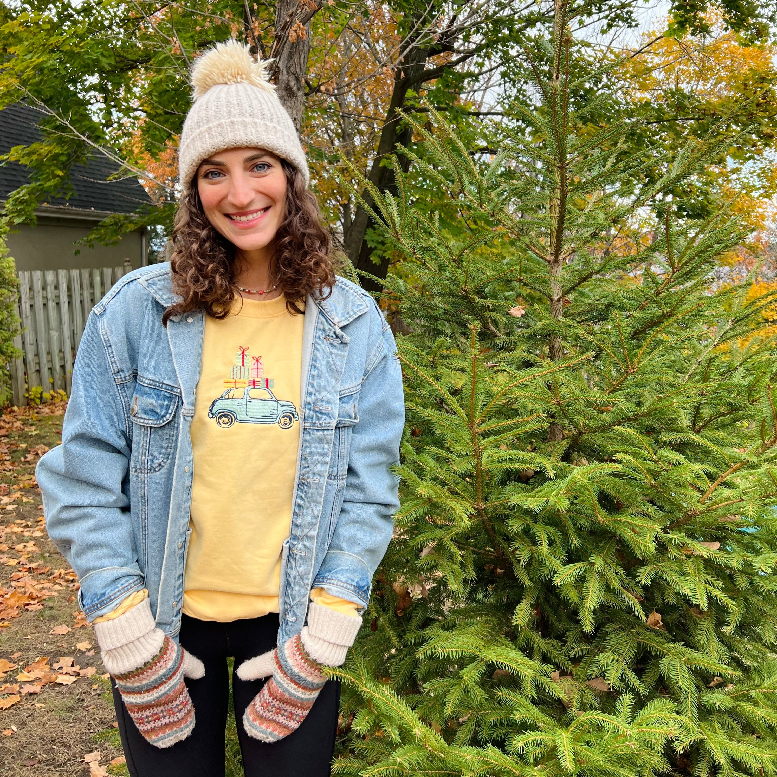 Person wearing a denim jacket and colorful sweatshirt in an outdoor setting.