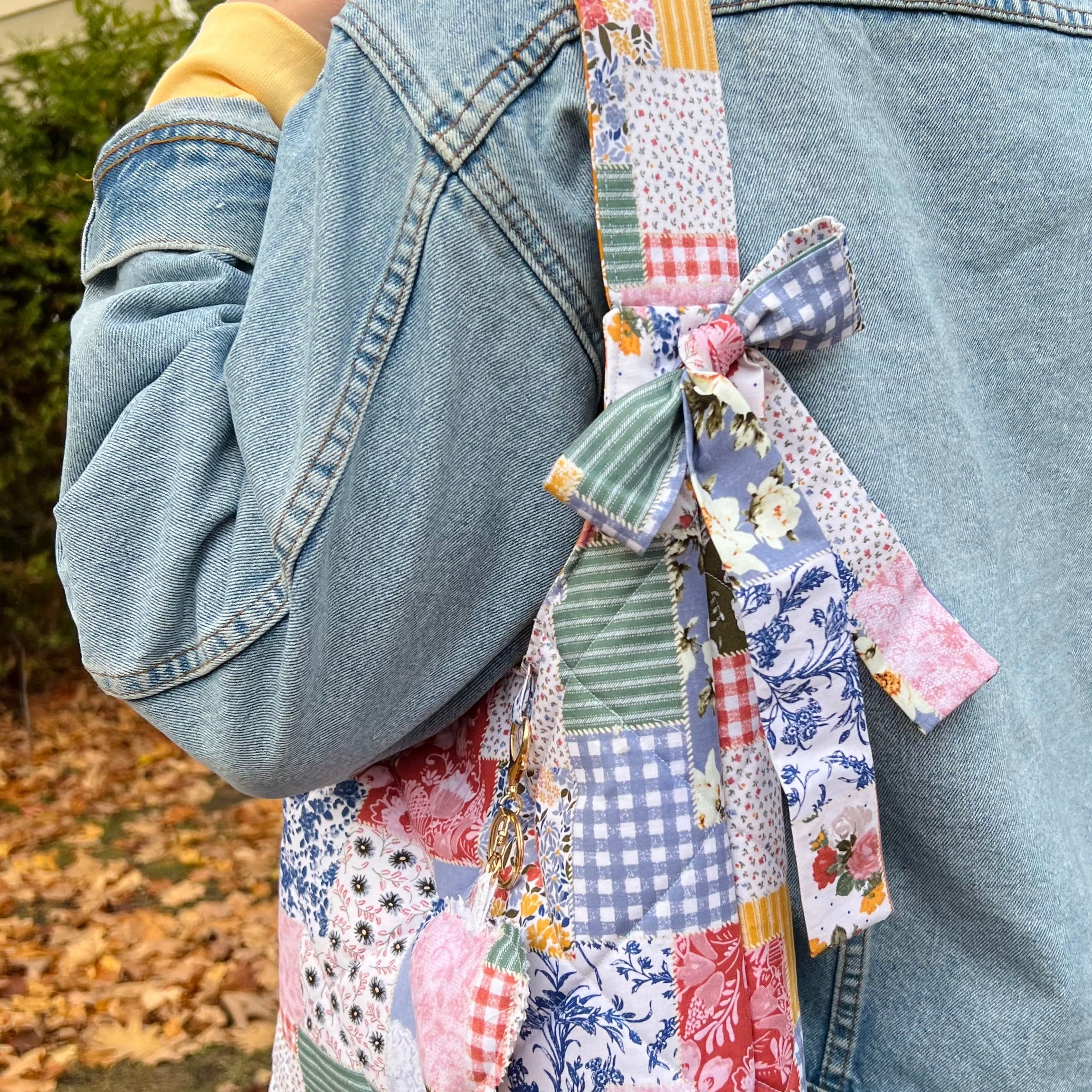 Person wearing a colorful patchwork bag with a denim jacket.