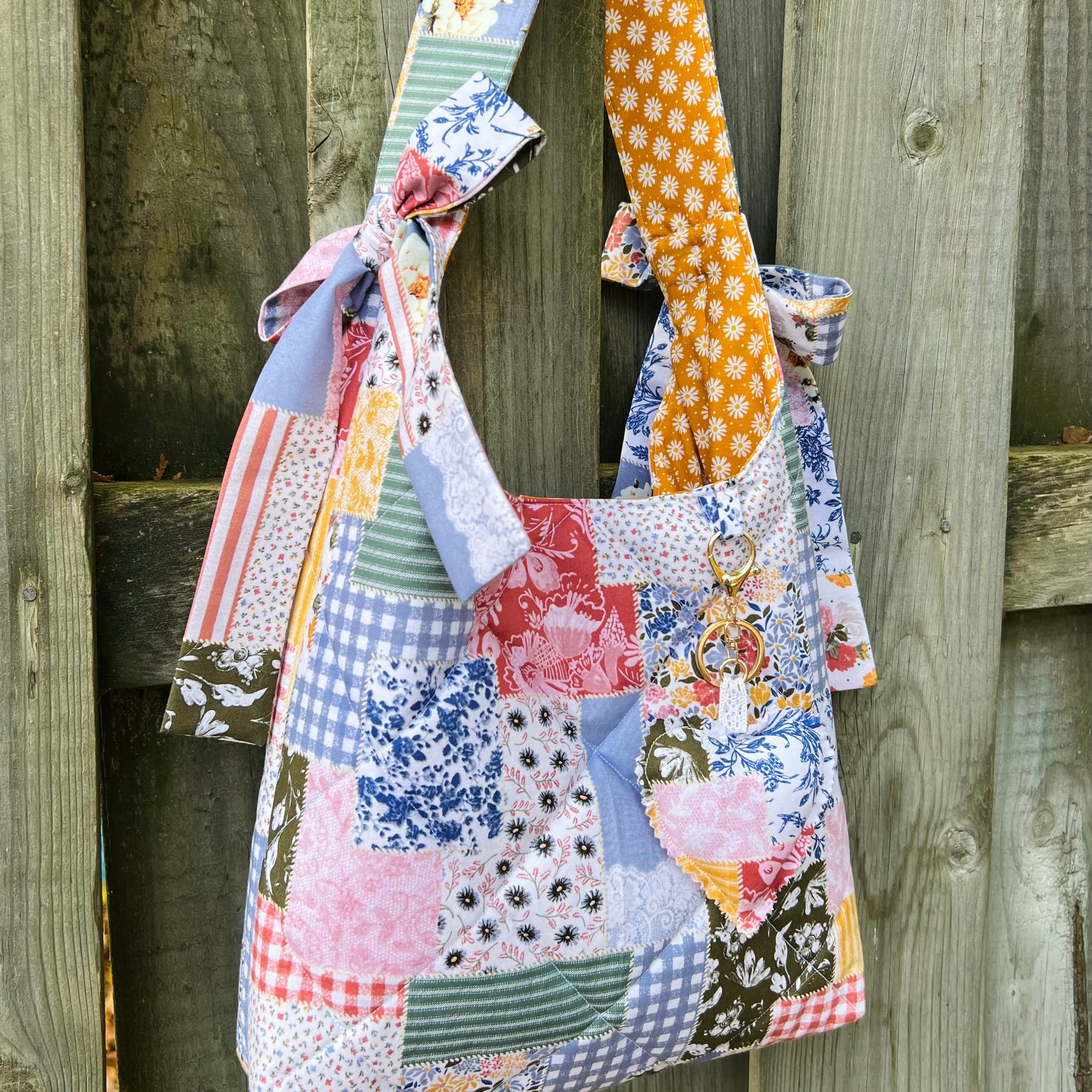 Colorful patchwork tote bag hanging on a wooden fence