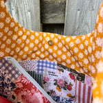 Load image into Gallery viewer, Fabric pouch with floral and checkered patterns on a wooden background
